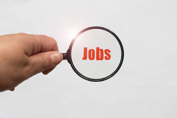 увеличительное стекло в руке и рабочие места слово на белом фоне. Концепция поиска работы
,