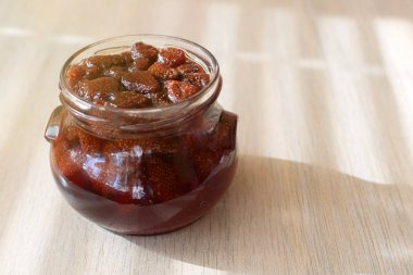 Çilek reçeli hafif ahşap arka plan üzerine açık kavanoz.