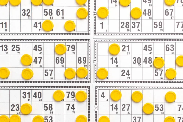 Old tabletop game lotto. Cards bingo and yellow game chips with numbers. Top view.