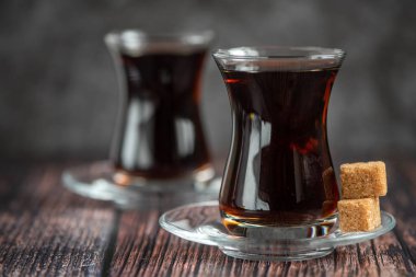 Türk cam çay bardak koyu ahşap masa üzerinde şeker kamışı ile için.