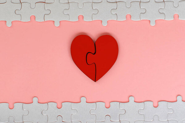 two piece red jigsaw love heart with white puzzle on pink background,love concept.