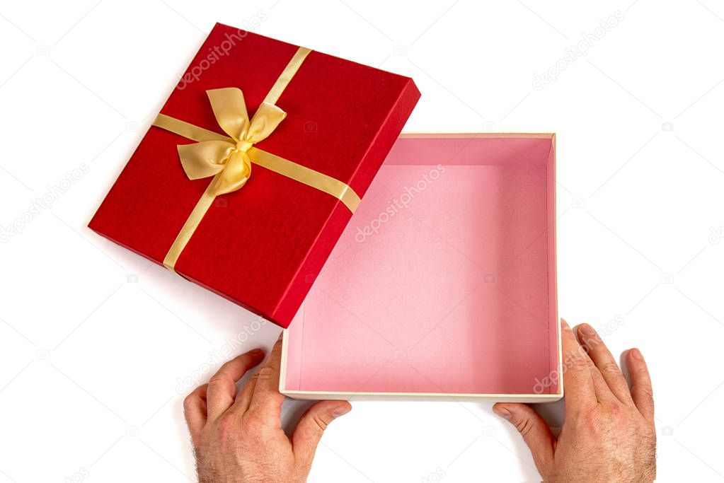 Open gift box with gold ribbon bow in men's hands, isolated on white.