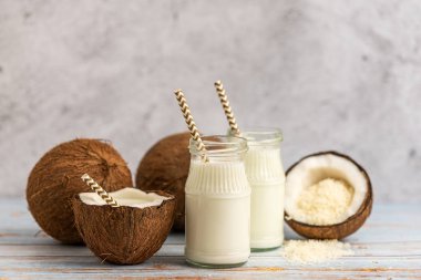 Hindistan cevizi, Hindistan cevizi sütü ve Hindistan cevizi pul hafif ahşap arka plan üzerinde kavanoz.