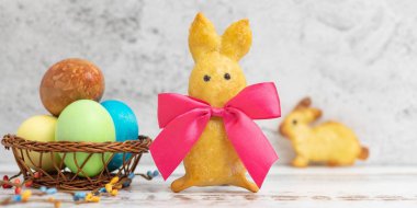 Ev yapımı tavşan şekilli kurabiye ve Paskalya yumurtaları hafif bir arka plan üzerinde kırmızı bir yayla