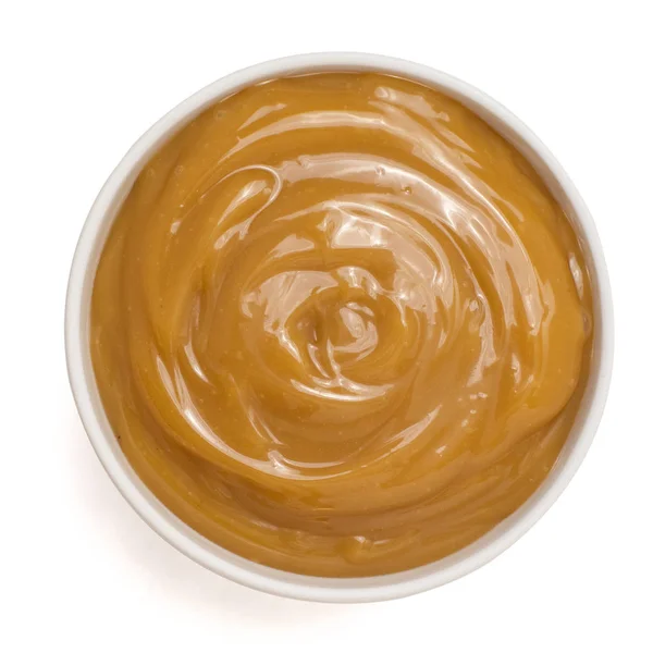 Sweet caramel sauce in bowl isolated on white background. Top view — Stock Photo, Image