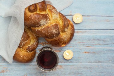 Şabat Shalom-Challah ekmek, Şabat şarap ve mavi ahşap arka planda mumlar. Üst görünüm. Boşluk Kopyala