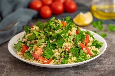 Bulgur ile Tabbouleh salata, maydanoz, bahar soğan ve domates gri arka planda kase. Üst görünüm. Kopya alanı ile
