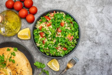 Bulgur ile Tabbouleh salata, maydanoz, bahar soğan ve domates gri arka planda kase. Üst görünüm. Kopya alanı ile