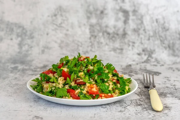 Tabbouleh sallad med bulgur, persilja, vårlök och tomat i skål på grå bakgrund. Topp-vy. Med kopierings utrymme — Stockfoto