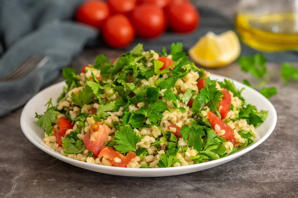 Bulgur ile Tabbouleh salata, maydanoz, bahar soğan ve domates gri arka planda kase. Üst görünüm. Kopya alanı ile