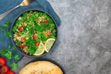 Bulgur ile Tabbouleh salata, maydanoz, bahar soğan ve domates gri arka planda kase. Üst görünüm. Kopya alanı ile