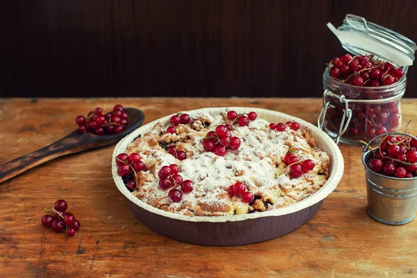 Leckere hausgemachte Torte und frische rote Johannisbeeren im Glas auf altem Holztisch — Stockfoto