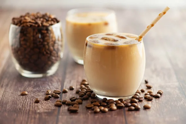 Cóctel de café con leche en vasos con cubos de café congelados sobre mesa de madera. Vista lateral — Foto de Stock