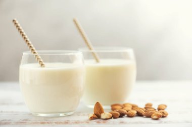 Açık ahşap masada badem ile bardaklarla badem sütü