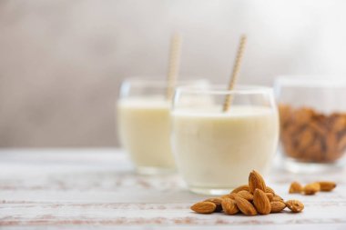 Açık ahşap masada badem ile bardaklarla badem sütü
