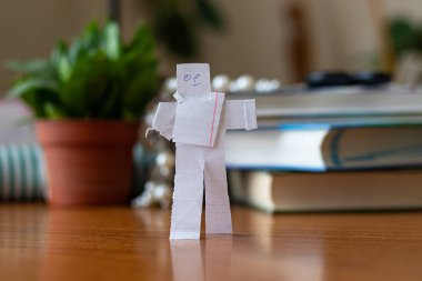 Kâğıt adamdan kesilmiş. Kitapların arka planında.