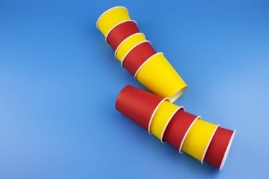 Mavi arka plan üzerinde çok renkli kağıt bardaklar.