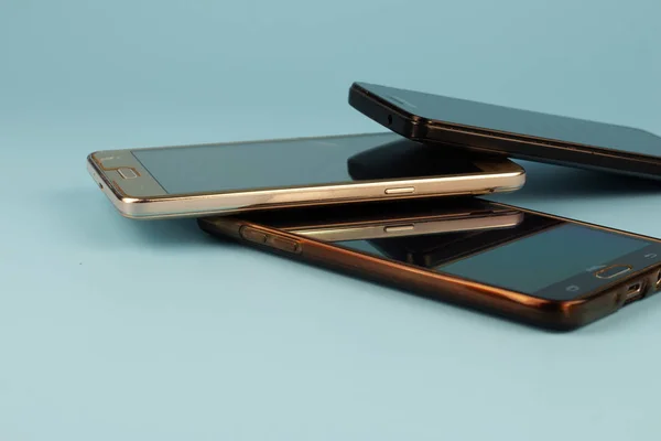 Mavi arka planda üç akıllı telefon.