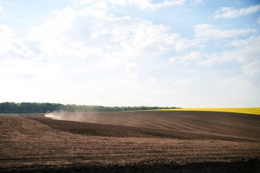 Kara topraklarla tarımsal işler. Mavi traktör biniciliği ve tohum ekme kırsalında. Kırsal bölgeler ilkbaharda çalışır. Çevre koruma kavramı. Ekolojik ürünler yetiştirme. Doğal arkaplan.