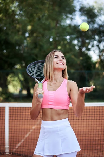 年轻的金发女子 身穿粉色上衣和白色裙子 夏天在球场上打网球 4的女运动员肖像 外面用网球拍和浅绿色的球训练 积极运动 — 图库照片