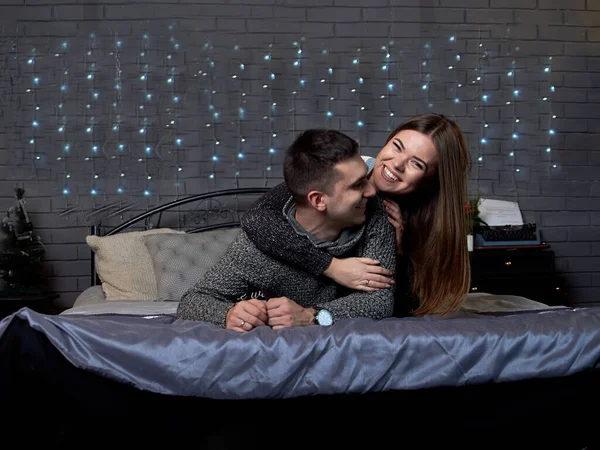 Unga Par Förälskade Liggande Sängen Med Julbelysning Bakom Omfamnande Kyssande — Stockfoto