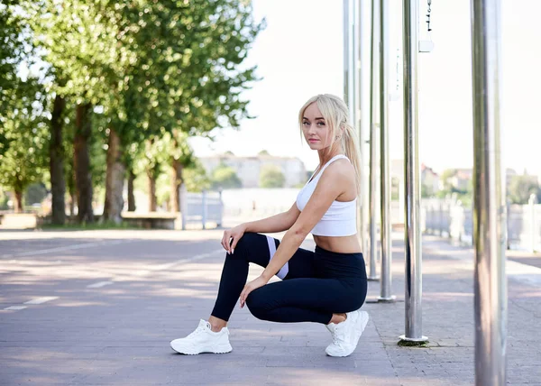 Giovane Donna Bionda Forma Con Top Bianco Leggings Neri Accovacciata — Foto Stock