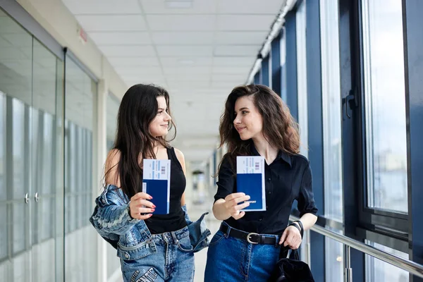国際パスポートと搭乗券を保持する2人の若いブルネットの女の子のクローズアップ写真は 軽い空港廊下文書管理でチケットを渡します 飛行機で旅する彼女たち — ストック写真