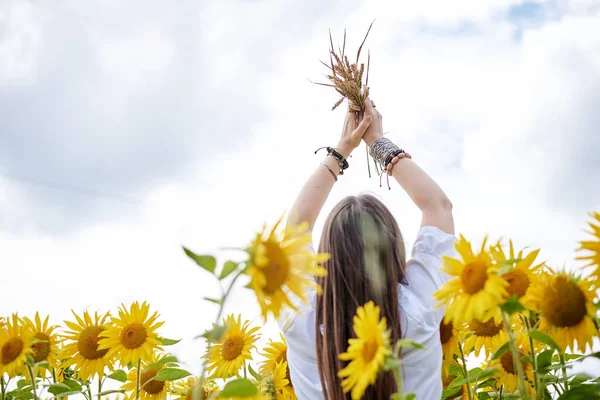 年轻的黑发女人 穿着波荷嬉皮衣 站在黄色向日葵地中间 拿着麦茎 自然背景的富有创意的女性肖像 生态旅游 — 图库照片