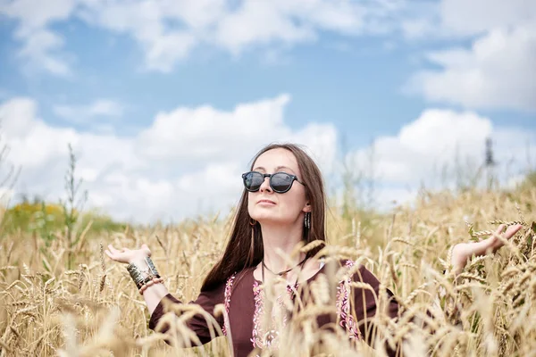 年轻的黑发嬉皮士女人 穿着波荷风格的衣服 坐在麦田中央蓝天 生态旅游概念 自然保护 — 图库照片