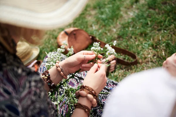 在阳光灿烂的夏日 女人戴着五彩缤纷的手镯 在绿地上做花香花环的特写照片 农村生态旅游 青年节手工制作的活动 — 图库照片