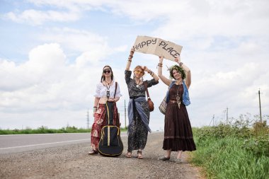Üç hippi kadın, boho tarzı kıyafetler giyiyorlar, yolda dikiliyorlar, başparmak gezdiriyorlar, kartonda Happy Place yazan bir yere otostop çekiyorlar. Arkadaşlar, yazın birlikte seyahat ediyoruz. Özgürlük ve mutluluk kavramı.