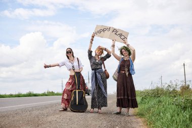 Üç hippi kadın, boho tarzı kıyafetler giyiyorlar, yolda dikiliyorlar, başparmak gezdiriyorlar, kartonda Happy Place yazan bir yere otostop çekiyorlar. Arkadaşlar, yazın birlikte seyahat ediyoruz. Özgürlük ve mutluluk kavramı.