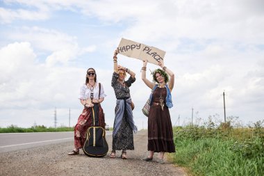 Üç hippi kadın, boho tarzı kıyafetler giyiyorlar, yolda dikiliyorlar, başparmak gezdiriyorlar, kartonda Happy Place yazan bir yere otostop çekiyorlar. Arkadaşlar, yazın birlikte seyahat ediyoruz. Özgürlük ve mutluluk kavramı.