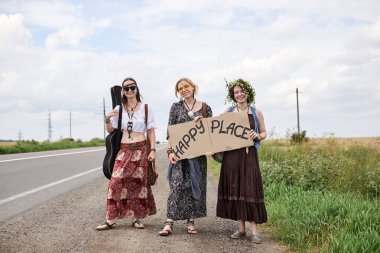 Üç hippi kadın, boho tarzı kıyafetler giyiyorlar, yolda dikiliyorlar, başparmak gezdiriyorlar, kartonda Happy Place yazan bir yere otostop çekiyorlar. Arkadaşlar, yazın birlikte seyahat ediyoruz. Özgürlük ve mutluluk kavramı.