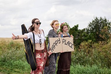 Üç hippi kadın, boho tarzı kıyafetler giyiyorlar, yolda dikiliyorlar, başparmak gezdiriyorlar, kartonda Happy Place yazan bir yere otostop çekiyorlar. Arkadaşlar, yazın birlikte seyahat ediyoruz. Özgürlük ve mutluluk kavramı.