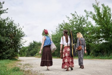 Üç hippi kadın, boho tarzı kıyafetler giyiyorlar, gitar tutuyorlar, kırsalda toprak yolda yürüyorlar. Arkadaşlar, yazın birlikte seyahat ediyoruz. Özgürlük ve mutluluk kavramı.
