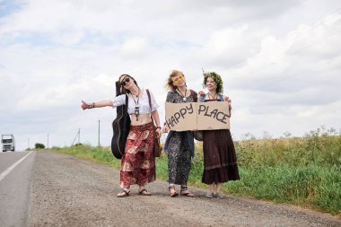 Üç hippi kadın, boho tarzı kıyafetler giyiyorlar, yolda dikiliyorlar, başparmak gezdiriyorlar, kartonda Happy Place yazan bir yere otostop çekiyorlar. Arkadaşlar, yazın birlikte seyahat ediyoruz. Özgürlük ve mutluluk kavramı.