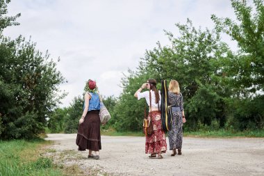 Üç hippi kadın, boho tarzı kıyafetler giyiyorlar, gitar tutuyorlar, kırsalda toprak yolda yürüyorlar. Arkadaşlar, yazın birlikte seyahat ediyoruz. Özgürlük ve mutluluk kavramı.