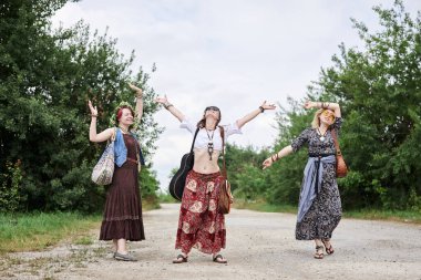 Üç hippi kadın, boho tarzı kıyafetler giyiyorlar, kırsalda toprak yolda yürüyorlar, dans ediyorlar, dinleniyorlar, eğleniyorlar. Arkadaşlar, yazın birlikte seyahat ediyoruz. Özgürlük ve mutluluk kavramı.