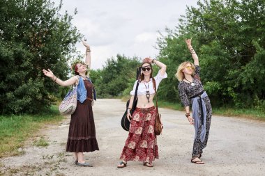 Üç hippi kadın, boho tarzı kıyafetler giyiyorlar, kırsalda toprak yolda yürüyorlar, dans ediyorlar, dinleniyorlar, eğleniyorlar. Arkadaşlar, yazın birlikte seyahat ediyoruz. Özgürlük ve mutluluk kavramı.