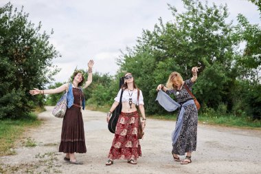 Üç hippi kadın, boho tarzı kıyafetler giyiyorlar, kırsalda toprak yolda yürüyorlar, dans ediyorlar, dinleniyorlar, eğleniyorlar. Arkadaşlar, yazın birlikte seyahat ediyoruz. Özgürlük ve mutluluk kavramı.