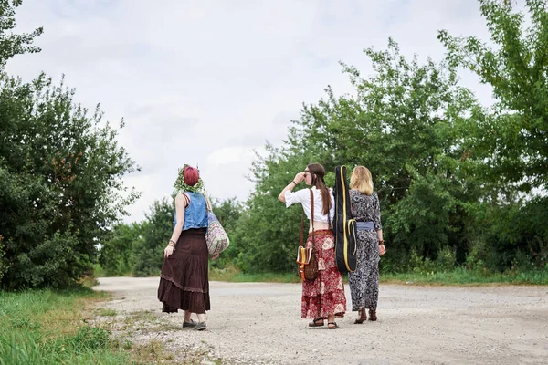 Üç hippi kadın, boho tarzı kıyafetler giyiyorlar, gitar tutuyorlar, kırsalda toprak yolda yürüyorlar. Arkadaşlar, yazın birlikte seyahat ediyoruz. Özgürlük ve mutluluk kavramı.