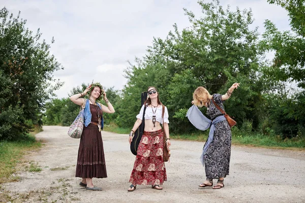 Üç hippi kadın, boho tarzı kıyafetler giyiyorlar, kırsalda toprak yolda yürüyorlar, dans ediyorlar, dinleniyorlar, eğleniyorlar. Arkadaşlar, yazın birlikte seyahat ediyoruz. Özgürlük ve mutluluk kavramı.