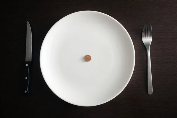 Healthy food, poverty, saving money: coins on a white plate at dining room