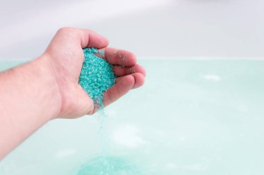 İnsanın el poring banyo tuz kristallerinin suya yakın. Kaplıca tedavisi, gevşeme