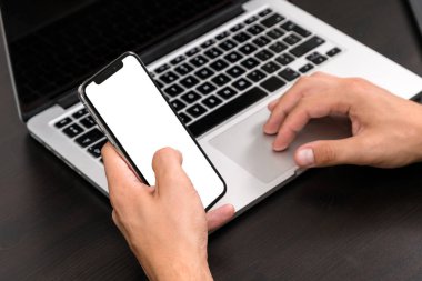 Antika ahşap masa dizüstü bilgisayar üzerinde çalışırken akıllı telefon yazarak eller mans. Tipik bir klavye üzerinde eller. Üstten görünüm, iş Ofis İşyeri