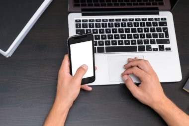 Antika ahşap masa dizüstü bilgisayar üzerinde çalışırken akıllı telefon yazarak eller mans. Tipik bir klavye üzerinde eller. Üstten görünüm, iş Ofis İşyeri