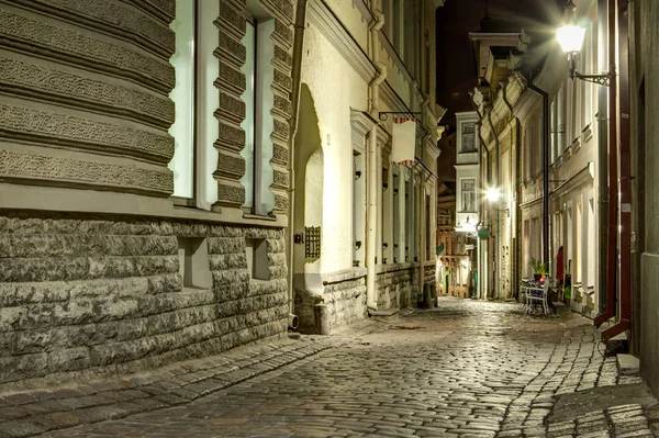 Narrow old town street of Tallinn, Estonia at night time. Stone pavement road with cosy city lights of historic city in Baltic states. Tourist attraction