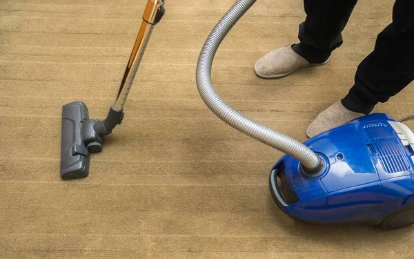 Dark head of a modern vacuum cleaner being used while vacuuming a rug. Cleaning service concept. Process of hoovering carpet with vacuum cleaner — Stock Photo, Image