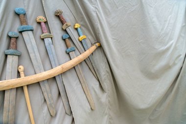 Ahşap el yapımı kılıçlar gri kumaş arka plan ipte asılı. Tarihi kavramı